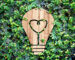 Light Bulb wood icon and heart shape inside on green leaf wall,Eco concept.